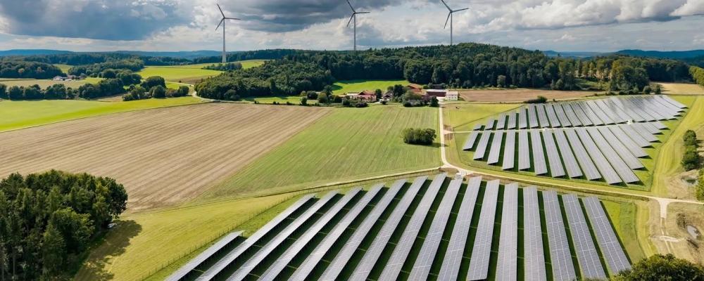 Bildtext: Den nya solparken Hatzenhof och vindparken Granswang (i bakgrunden) matar in el i Ørsteds transformatorstation i Raitenbuch. Foto: Ørsted