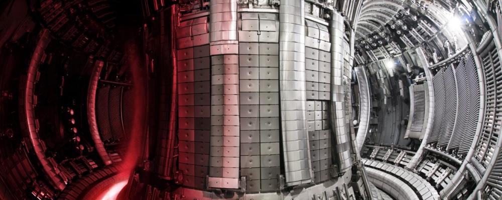En tokamak, som på bilden, är en avancerad reaktortyp som används för att försöka producera energi genom kärnfusion – samma process som driver solen. I anläggningen ITER i södra Frankrike byggs världens största tokamak. Principen bygger på att väteisotoper hettas upp till extremt höga temperaturer så att de blir plasma. Detta plasma hålls svävande med hjälp av starka magnetfält i en ringformad kammare, så att det inte kommer i kontakt med väggarna. Målet är att få atomkärnor att slå samman och frigöra energi. Tokamaken i ITER ska visa att fusion kan ge mer energi än vad som krävs för att starta processen. Tekniken är dock mycket komplex. Utmaningar handlar om stabilitet i plasmat, material som tål värmen och enorma kostnader. ITER är ett forskningsprojekt – inte ett kommersiellt kraftverk. Foto: ITER
