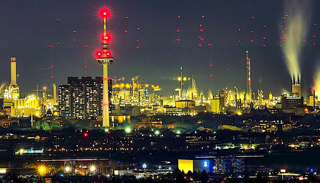 Telekommunikationstornet i Mannheim, med de tre höghusen vid floden Neckar. 18 kilometer bakom syns de röda varningsljusen från vindkraftverk vid Großniedesheim i Rheinland-Pfalz (vid god sikt från Heidelberg). Foto: Wikipedia Common, kredit: Georg Buzin
