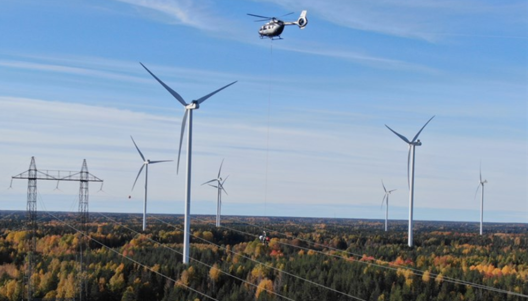 I en vajer under helikoptern hänger montörerna och monterar flygvarningskloten på den spänningssatta linan. Foto: Vattenfall Services
