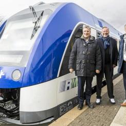 Tyska kollektivtrafikbolaget satsar på tillfälliga lösningar för RB15-linjen. Rhein-Main-Verkehrsverbund (RMV) står inför en utmanande period när bränslecellsdrivna tåg på RB15-linjen ersätts med dieseldrivna enheter under hela 2025. På bilden ses RMV:s styrelseordförande Ulrich Krebs, verkställande direktör Knut Ringat och Usingens borgmästare Steffen Wernard vid Usingen station tillsammans med ett tåg från RB15-linjen. 
De bränslecellsdrivna tågen, som infördes för att minska beroendet av fossila bränslen, har visat sig vara opålitliga under sina två första år i drift. Det har lett till omfattande trafikstörningar och nödlösningar med dieseldrivna tåg. RMV arbetar nu med tillfälliga lösningar för att säkerställa stabil trafik för passagerarna på linjen. Foto: Arne Landwehr/RMV