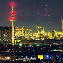 Telekommunikationstornet i Mannheim, med de tre höghusen vid floden Neckar. 18 kilometer bakom syns de röda varningsljusen från vindkraftverk vid Großniedesheim i Rheinland-Pfalz (vid god sikt från Heidelberg). Foto: Wikipedia Common, kredit: Georg Buzin