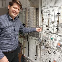 Professor Pär Olsson visar ugnen som når upp till 2000 grader, i vilken man tillverkar kärnbränslepulver. Här sker omvandlingen från uranmetall till uranhydrid (med tillförsel av vätgas) och till urannitrid (med tillförsel av kvävgas). Bild: Städje.